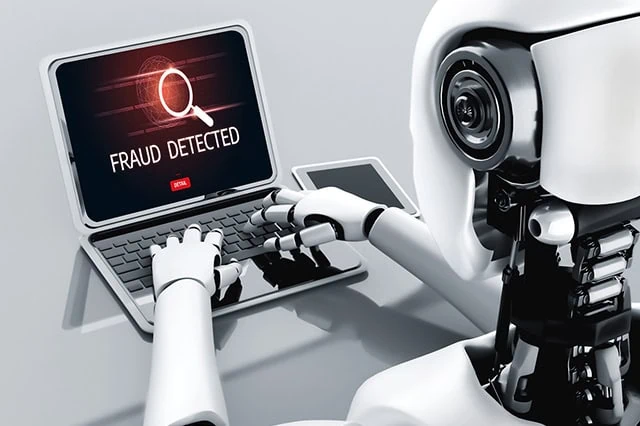 a robot is typing on a laptop while the screen says fraud detected.