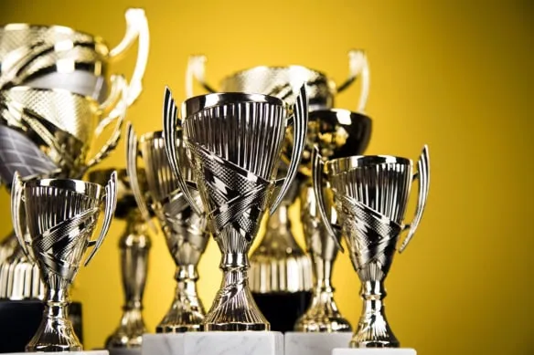 trophies of various sizes and shapes are up against a yellow background.