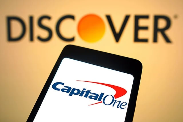the discover logo is shown above a phone displaying the capital one logo representing a merger between the two companies.