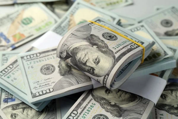 Many hundred dollar bills against a light background.