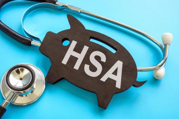 a stethoscope wrapped around a flat wooden piggy bank carving that says H S A.