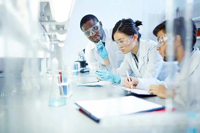 10 Monthly Dividend Stocks for Frequent, Regular Income 12 scientists work in a laboratory.