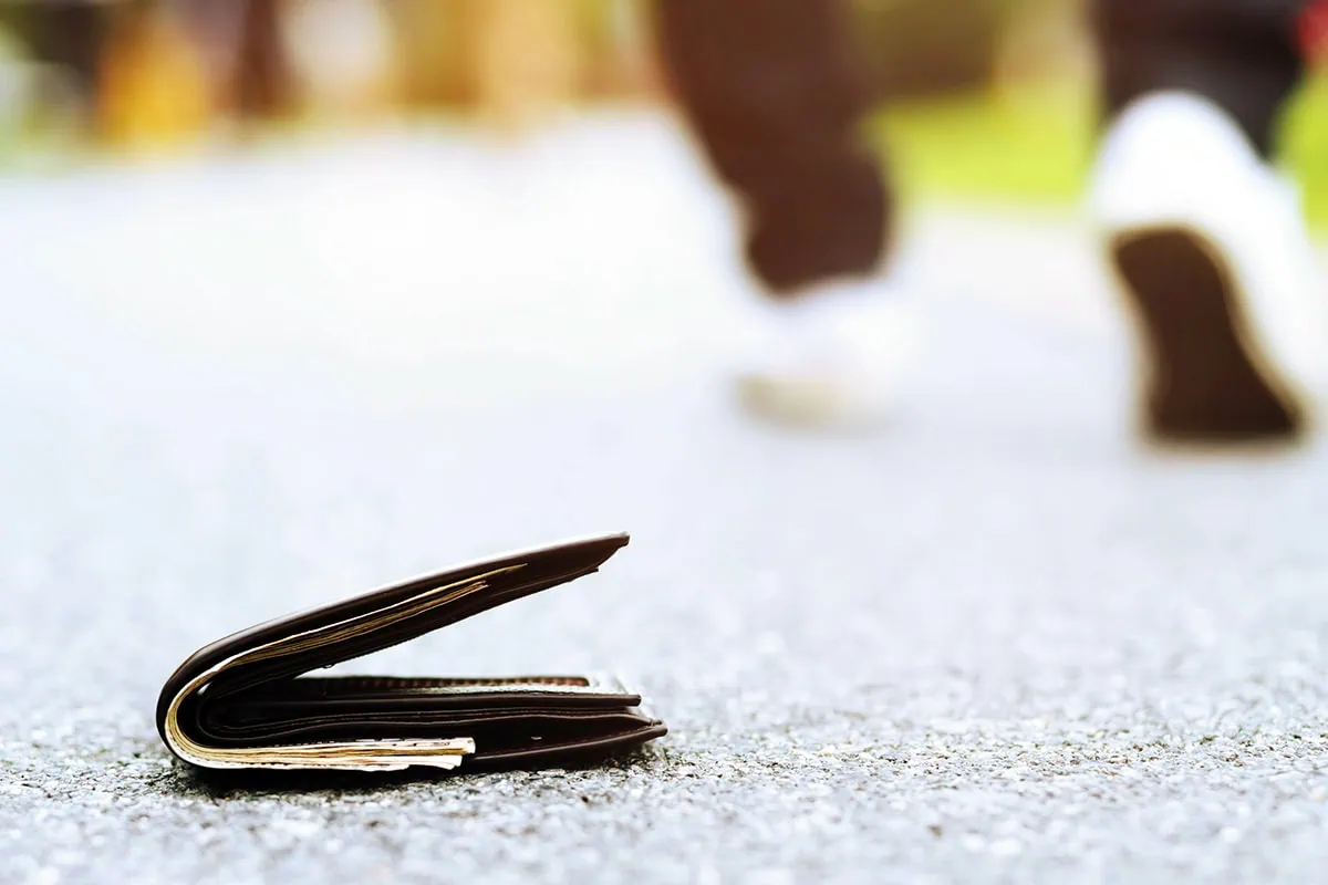 a person leaves a wallet behind on the ground.