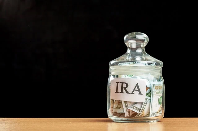 Are RMDs Required If You're Still Working? 3 the word IRA is written on a glass jar with money in it.