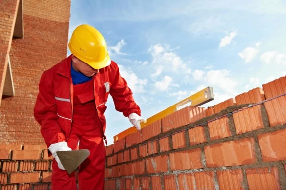 a construction worker lays bricks.