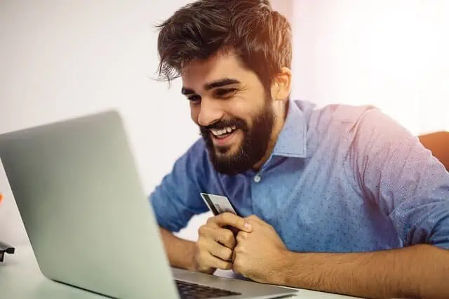What is a Credit Utilization Rate and How Does it Affect Credit? 5 man smiling at computer with credit card in hand