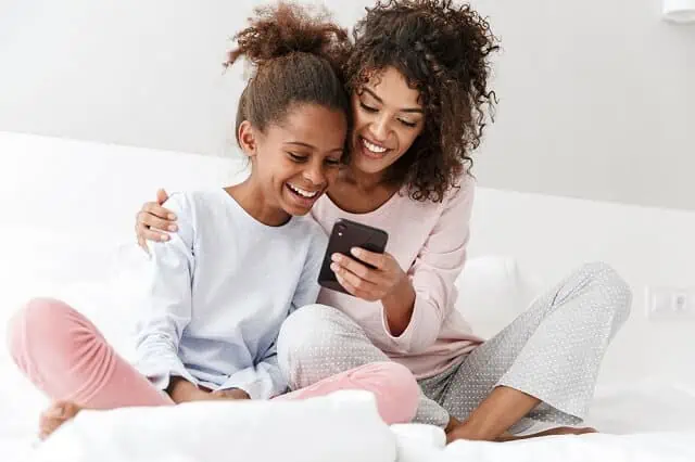 What's the Minimum Age for an Authorized User on a Credit Card? 3 mother and daughter on bed looking at phone