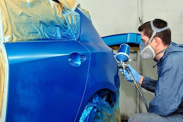 14 Dividend Kings for Royally Resilient Income 7 a worker spray-paints a car blue.