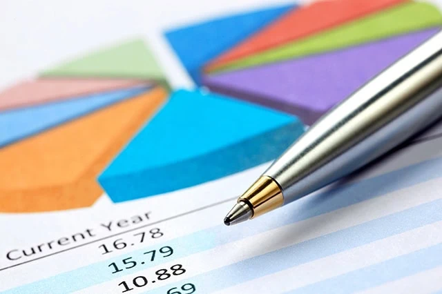 10 Monthly Dividend Stocks for Frequent, Regular Income 13 a pen resting on a mutual fund report with a pie chart and several return figures.
