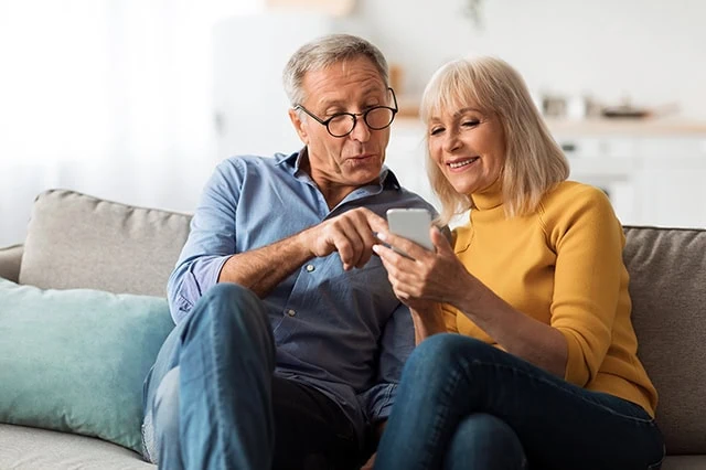 Are Financial Advisors Only for Inexperienced Investors? 9 a happy older couple looking at a smartphone.