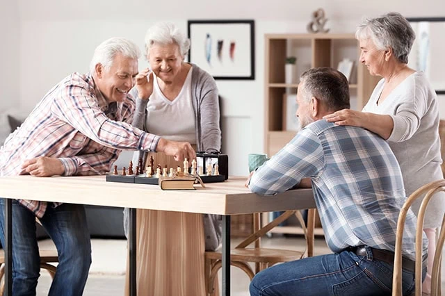 The Best REITs You Can Buy in 2025 3 residents of a senior housing building play chess.